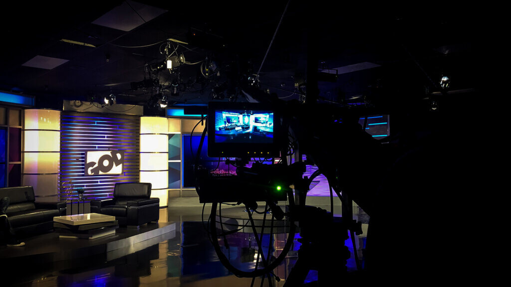 Professional broadcast studio setup with lighting, cameras, and multi-monitor control station