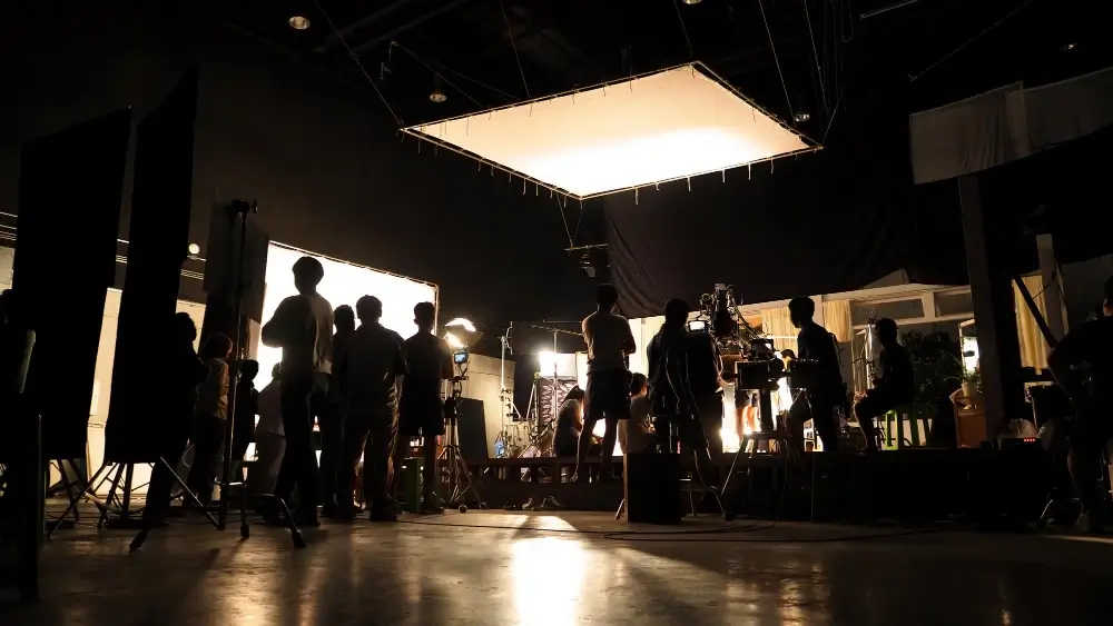A bustling film set in action—Florida’s film-friendly climate, skilled workforce, and diverse locations make it a top choice for productions of all sizes. Behind-the-scenes view of a film crew working on a brightly lit indoor set, showcasing a professional production environment with lighting rigs, crew, and equipment.