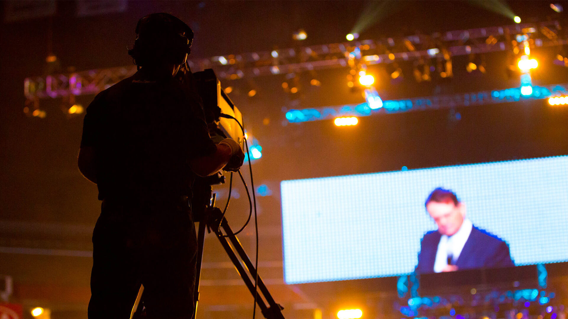 Cameraman filming a speaker at a large-scale conference with LED screen backdrop