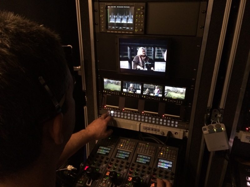 Video technician adjusting camera feed levels using waveform monitor and color correction tools