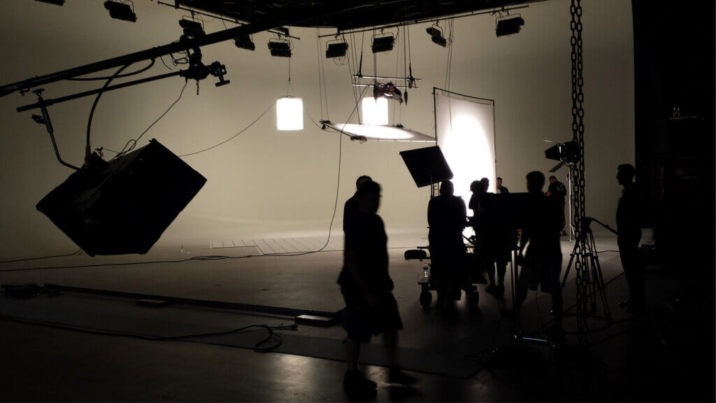 Video production studio setup with lighting rigs, camera crew, and backdrop equipment