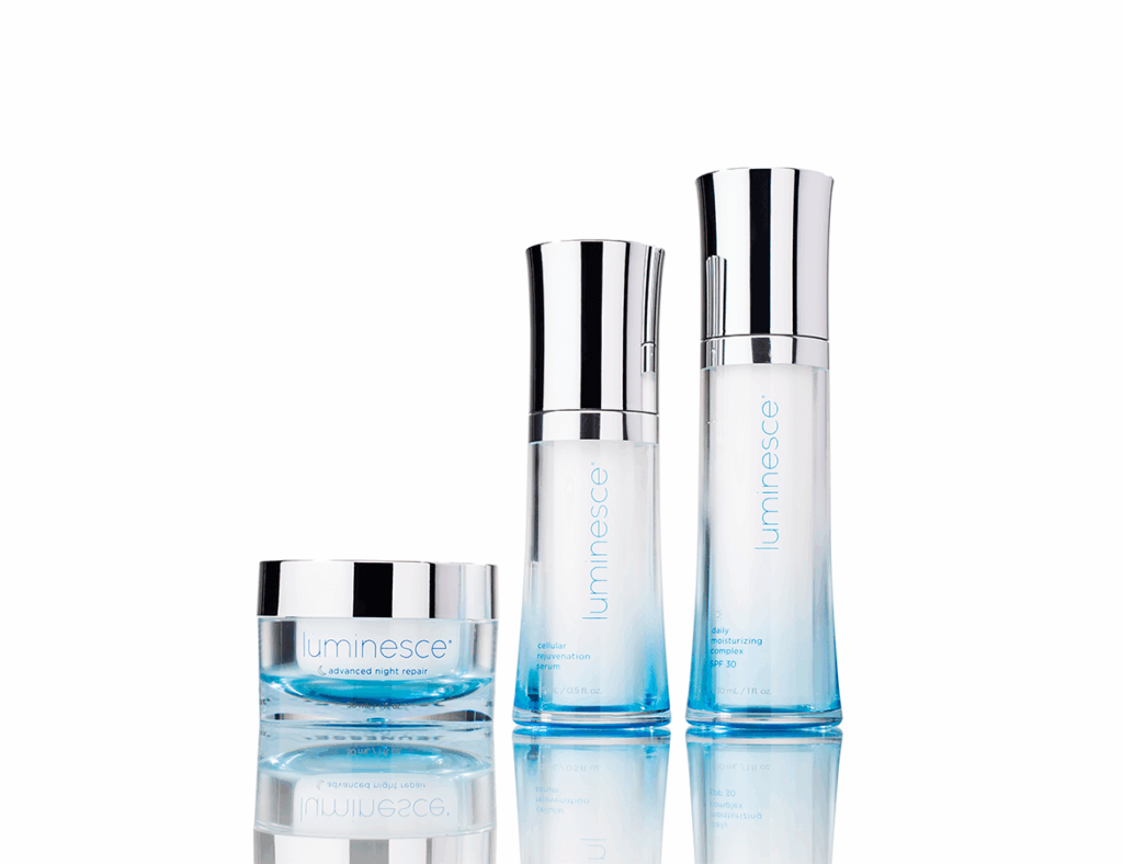 Image showing: Three Luminesce skincare products with sleek silver caps, featuring a blue and white color scheme, displayed on a reflective surface.