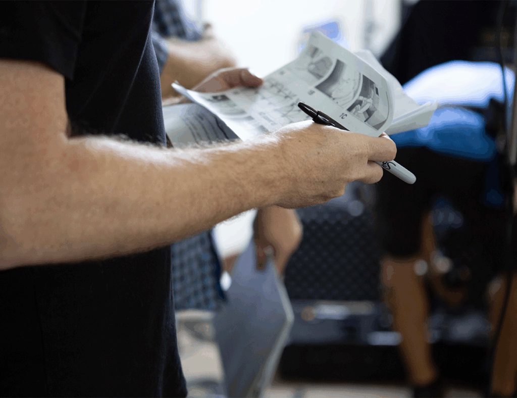 A close up of a video producer holds a paper packet of story boards and marker in his hands.